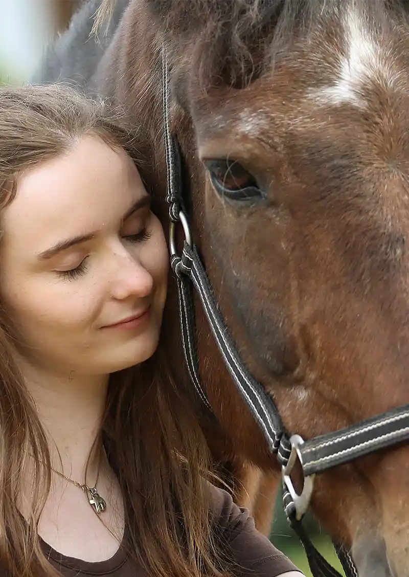 Frau schmiegt sich an Pferd